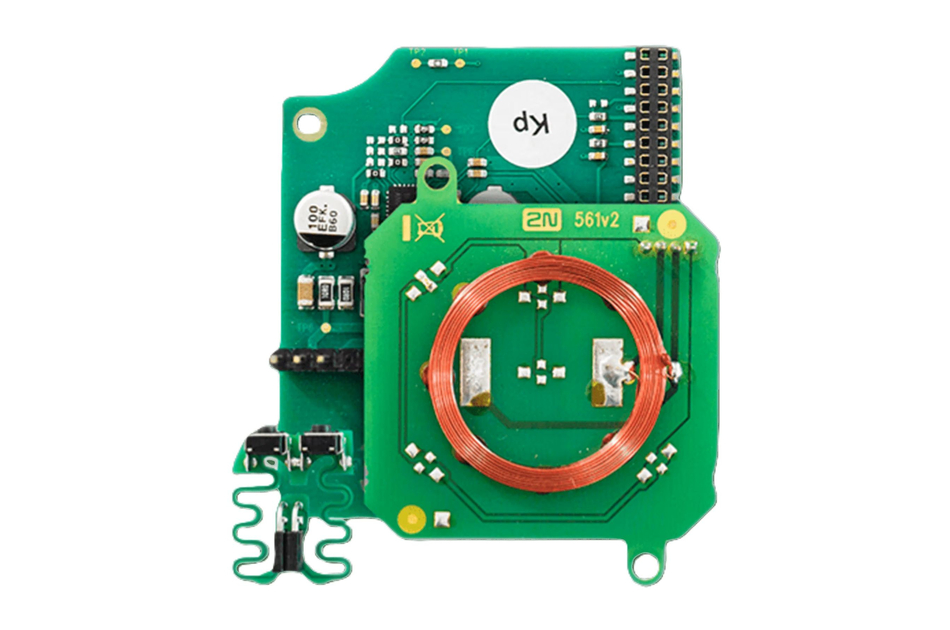 Elektronische Leiterplatte mit einer Kupferspule in der Mitte und verschiedenen elektronischen Komponenten.