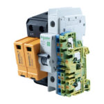 Sicherheitsvorrichtung mit mehreren elektrisch verbundenen Komponenten, darunter ein Schalter und farbige Klemmen.
