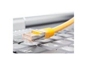Ein gelbes Ethernet-Kabel liegt auf einer Computertastatur.