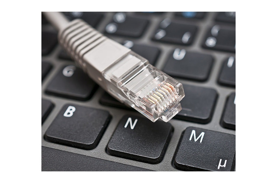 Ein Ethernet-Kabel liegt auf einer Computertastatur, wobei der Stecker deutlich zu sehen ist.