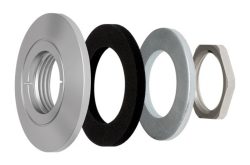 Einzelteile einer mechanischen Vorrichtung: Vier Teile, darunter eine silberne Metallkappe, eine schwarze Dichtung, eine graue Unterlegscheibe und eine sechseckige Mutter.
