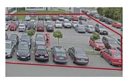 Ein Parkplatz mit mehreren Autos und einem eingekreisten Bereich, der einen Mann zeigt, der sich in der Nähe eines Autos befindet.