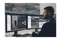 Ein Mann überwacht mehrere Bildschirme mit Sicherheitssystem-Software und Überwachungsbildern.