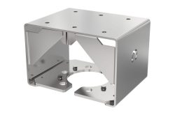 Ein silbernes, kubisches Metallbauteil mit mehreren kreisförmigen Bohrungen und abgekanteten Kanten.