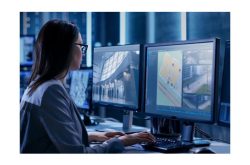 Eine Frau arbeitet in einem modernen Überwachungsraum an mehreren Computerbildschirmen.