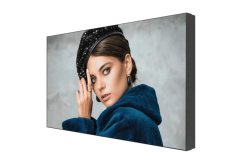 Eine Frau in einem blauen Mantel und schwarzem Hut auf einem digitalen Display.