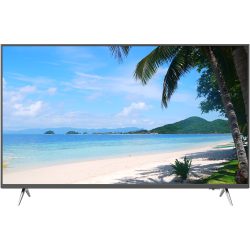 Ein Flachbildfernseher zeigt ein Bild von einem tropischen Strand mit weißem Sand, Palmen, klarem blauem Wasser und einem bewaldeten Hügel im Hintergrund.