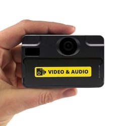 Eine Hand hält eine kleine schwarze Kamera, die ein gelbes Etikett mit der Aufschrift "VIDEO & AUDIO" trägt.
