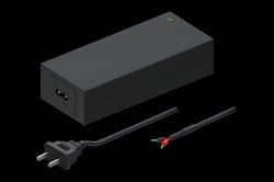 Rechteckiges schwarzes Netzteil mit einem grünen Indikatorlicht auf der Oberseite, einem Stromkabelanschluss und zwei separaten Kabeln, eines mit einem Stecker und das andere mit offenen Kabelenden.